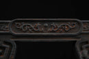 Texture in legno scuro decorata con motivi intagliati elaborati sul supporto per katana, primo piano dettagliato. Supporto Katana Douu.