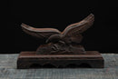 Supporto in legno scuro con aquila ad ali spiegate finemente intagliata, su sfondo nero. Supporto Katana Washi.