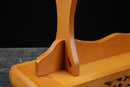 Primo piano di un supporto per katana in legno con finitura liscia marrone chiaro, base finemente intagliata, vista laterale. Supporto Katana Taiyou.
