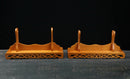 Due supporti per katana in legno decorati con intagli elaborati su sfondo scuro; Supporto Katana Taiyou.
