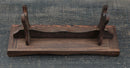 Supporto per katana in legno marrone scuro con sostegni curvi e venature dettagliate su una superficie testurizzata. Supporto Katana Mokuzai.