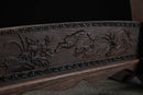 Dettaglio del supporto per katana in legno, motivi floreali intagliati con bordi elaborati in legno marrone scuro, vista angolata. Supporto Katana Keshiki.