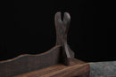 Supporto per katana in legno scuro con sostegno curvo, esposto su una superficie testurizzata con sfondo nero. Supporto Katana Mokuzai.