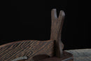 Primo piano di un supporto per katana in legno scuro, con eleganti venature su sfondo nero. Supporto Katana Otera.