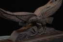 Aquila intagliata in legno scuro con piume dettagliate e artigli che afferrano una base, vista angolata con texture ricca; edizione supporti per katana. Supporto Katana Washi ...