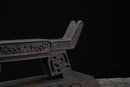 Primo piano di un supporto per katana in legno scuro finemente intagliato su sfondo nero, che mostra dettagli e motivi decorativi. Supporto Katana Douu.