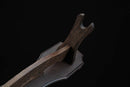 Primo piano di un supporto per katana in legno scuro con venature dettagliate, inclinato verso l'alto su sfondo nero. Supporto Katana Otera, supporto per katana.