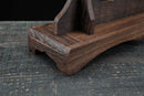 Supporto per katana in legno scuro rustico con venature elaborate su una superficie in legno testurizzata. Supporto Katana Mokuzai.